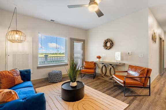 a living room with a blue couch and chairs and a desk with a window at 41 North Senior Living Apartments, Fort Wayne, IN