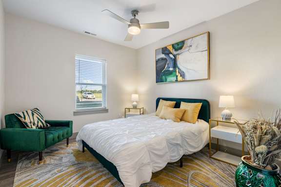 a bedroom with a bed and a chair and a ceiling fan at 41 North Senior Living Apartments, Indiana 46835