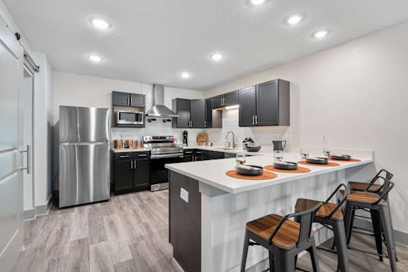 redesigned kitchen with stainless steel appliances and a large island with stools at Morada at Maysville Apartments, Fort Wayne, 46815