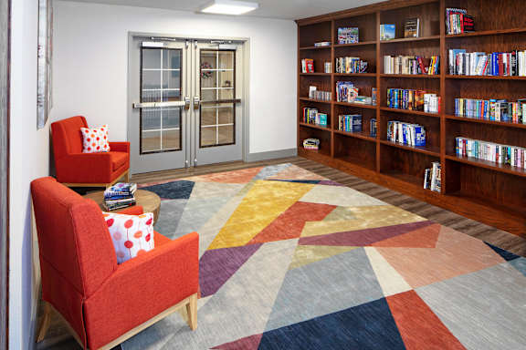 a library with red chairs and a colorful rug at Ritchey Reserve Apartments, Indiana