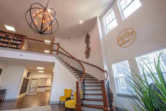a stairway in the lobby with a wooden railing and a large window at Ritchey Reserve Apartments, Fishers, 46038