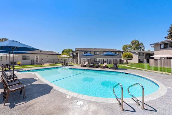 A swimming pool surrounded by a metal fence and a few chairs.