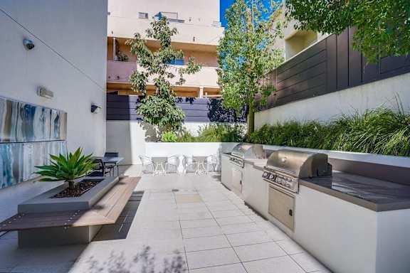 A modern outdoor patio with a bench, table, and plants.at Vues on Gordon, Los Angeles