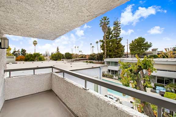 the view from the balcony of a condo with a pool and trees
