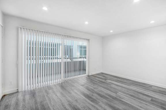 an empty living room with a white wall and a sliding glass door