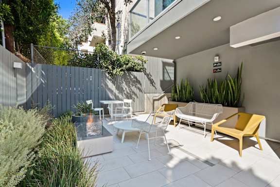 a patio with chairs and tables and a blue fence