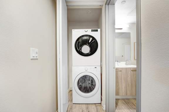 A white front loading washing machine in a laundry room.at The Blvd Lofts, Encino, CA