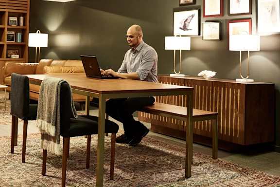 A man is sitting at a table with a laptop.