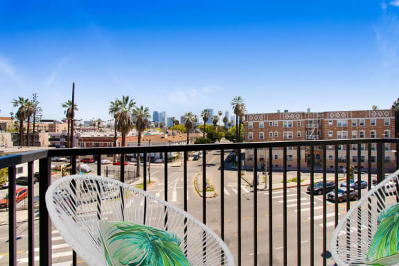 a balcony with two white chairs and a view of a parking lot