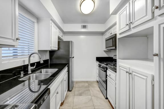 a kitchen with white cabinets and black counter tops and a sink