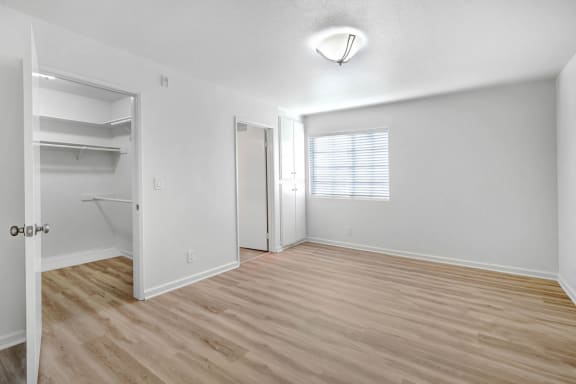 an empty living room with a closet and a window
