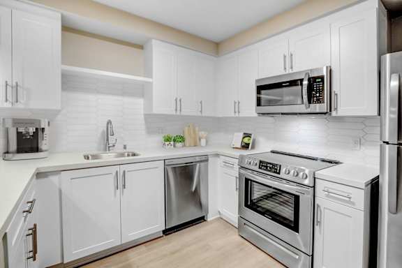 a white kitchen with stainless steel appliances and white cabinets