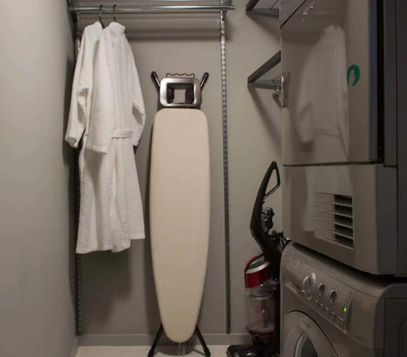 A white bathrobe is hanging on a rack next to a washing machine.