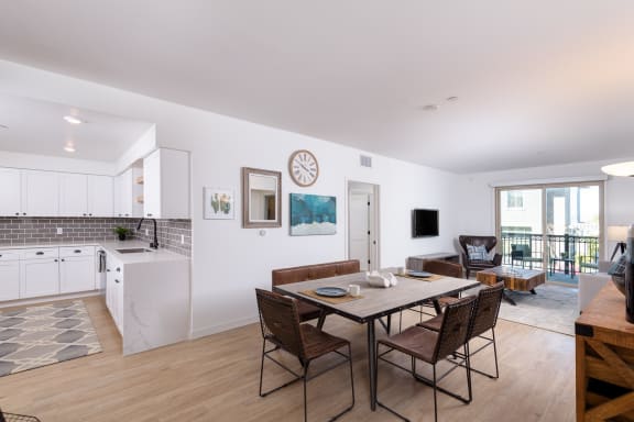 a dining room with a table and chairs and a kitchen with white cabinets