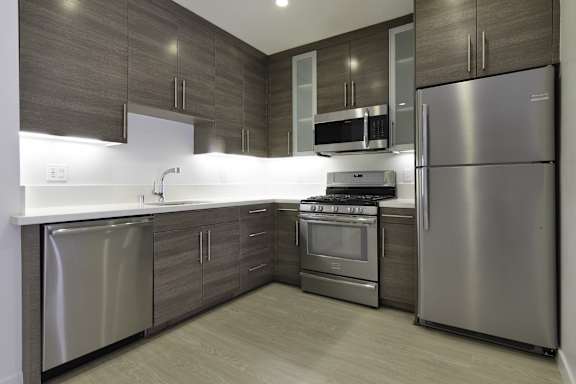 a kitchen with stainless steel appliances and wooden cabinets at Seventh West Apartments, Santa Monica, CA