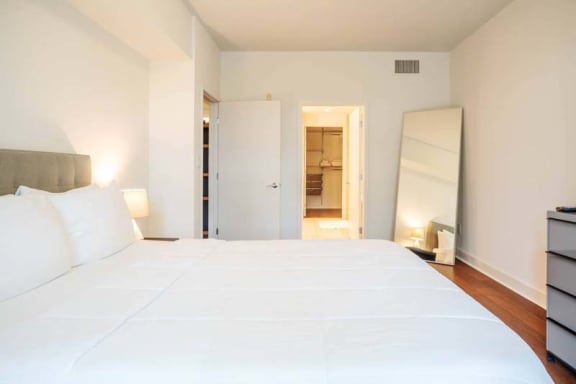 a large white bed in a room with a mirror