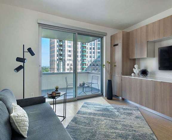 a living room with a couch and a tv and a balcony a living room with a couch and a tv and a balcony at Wilshire Margot, Los Angeles, CA