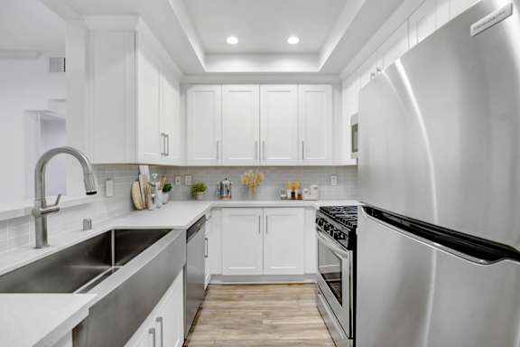 the kitchen has stainless steel appliances and white cabinets