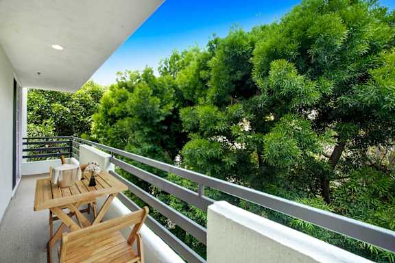 a balcony with a table and chairs and a view of trees