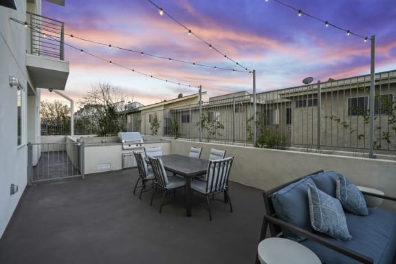 a patio with a table and chairs and a sunset in the background