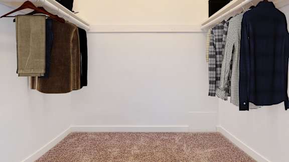 a closet with clothes hanging on the wall and a carpet