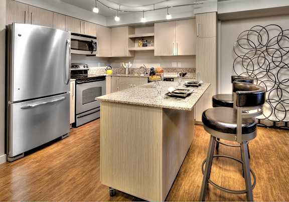 Modern kitchen with island and stainless steel appliances at The Lyric Apartments, Seattle, 98102