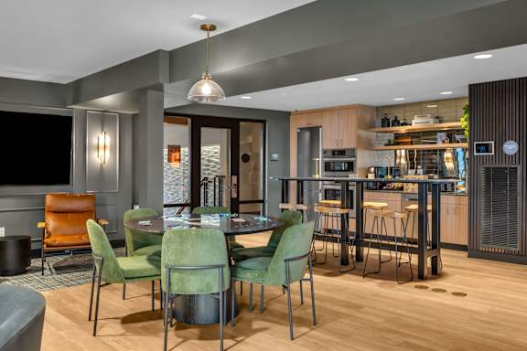 A modern dining room with a wooden table and green chairs.