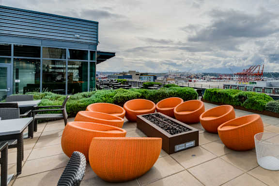A modern outdoor seating area with orange chairs and a table.