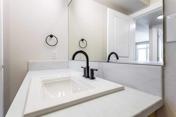 A white sink in a bathroom with a black faucet.