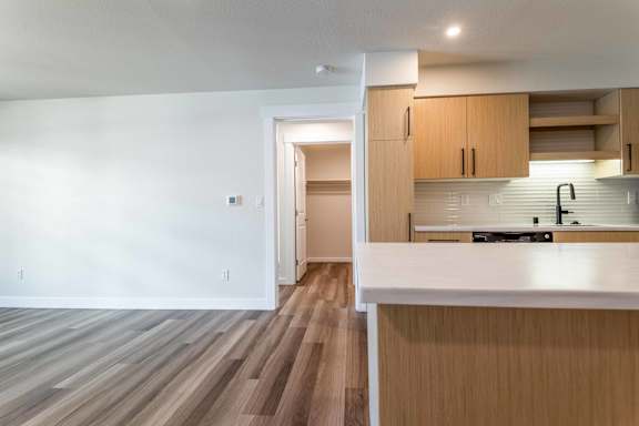 Open concept kitchen and living area with wood flooring at The Lyric Apartments, Seattle, WA 98102