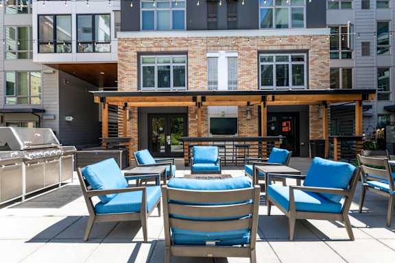A patio with blue chairs and a table with a blue cushion.