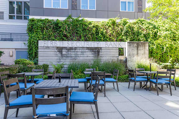 A patio with tables and chairs in front of a building with a sign that says