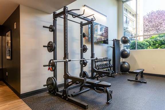 Home gym with power rack and weight equipment at The Lyric Apartments, Seattle, Washington