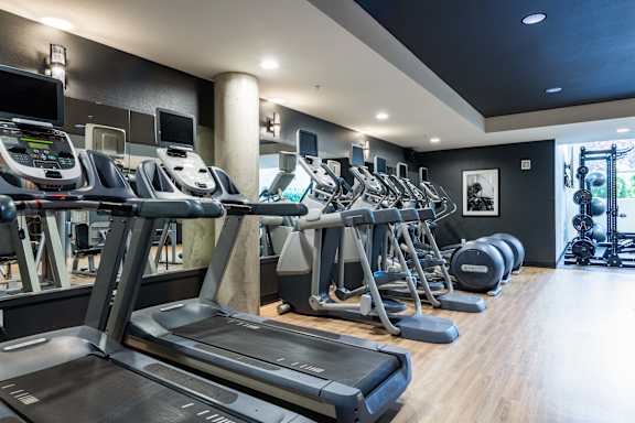 Fitness center with cardio equipment and free weights at The Lyric Apartments, Seattle