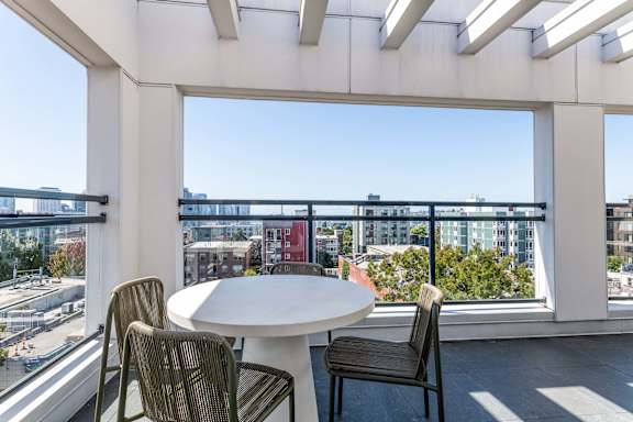 A balcony with a table and chairs overlooking a cityscape.