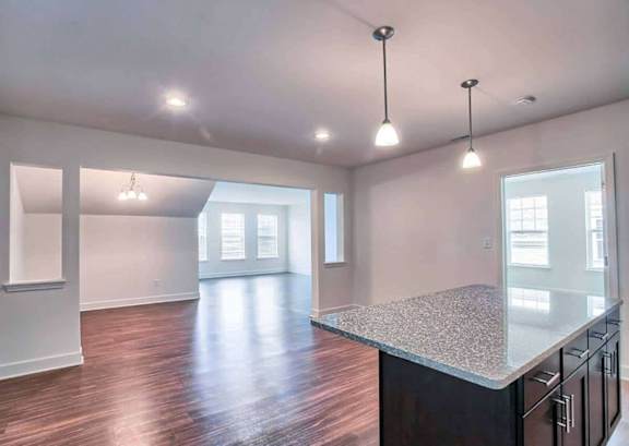 A spacious kitchen with dark wood floors and a granite countertop.