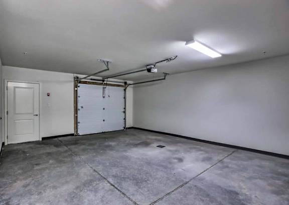 A large empty room with a door and a garage door.