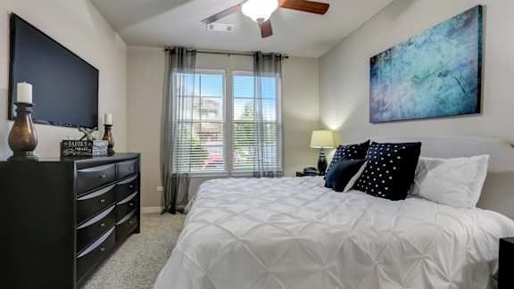 A bedroom with a large bed, a dresser, and a painting on the wall.