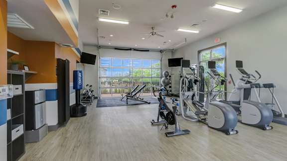 A gym with a variety of exercise equipment and a large window.