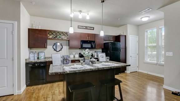 A kitchen with a brown countertop and a black chair.