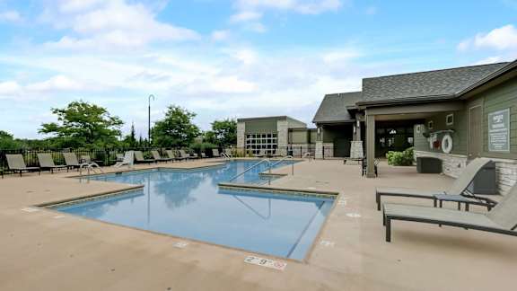 A large swimming pool with lounge chairs and a building in the background.