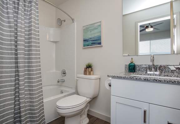 A bathroom with a toilet, sink, and shower curtain at Liberty Square Apartments - Saltlake City, UT Apartments, Saltlake City, 84102