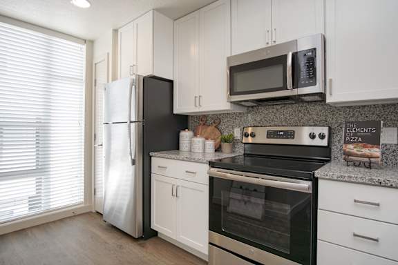 A modern kitchen with stainless steel appliances and white cabinets. at Liberty Square Apartments - Saltlake City, UT Apartments, Apartments, Saltlake City, UT