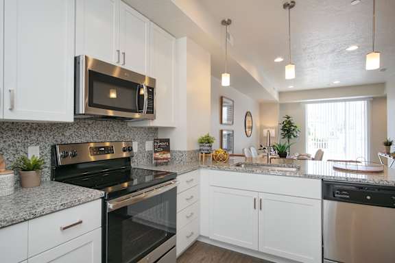 A kitchen with white cabinets and a black stove top oven. at Liberty Square Apartments - Saltlake City, UT Apartments, Utah, 84102