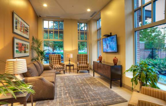 Liberty Gateway Apartments, Salt Lake City, UT, A living room with a brown sofa, a grey armchair, a wooden cabinet, a rug, a potted plant, and a television.