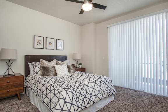 A bedroom with a bed, two lamps, and a ceiling fan at Liberty Square Apartments - Saltlake City, UT Apartments, Saltlake City, UT, 84102