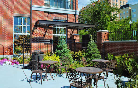 Liberty Gateway Apartments, Salt Lake City, UT, A patio with a table and chairs is surrounded by green plants.