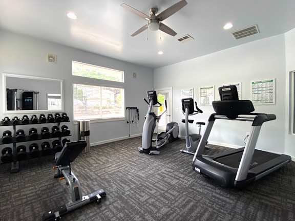 Modern fitness center with treadmill and free weights at Liberty Hill Apartments, Utah