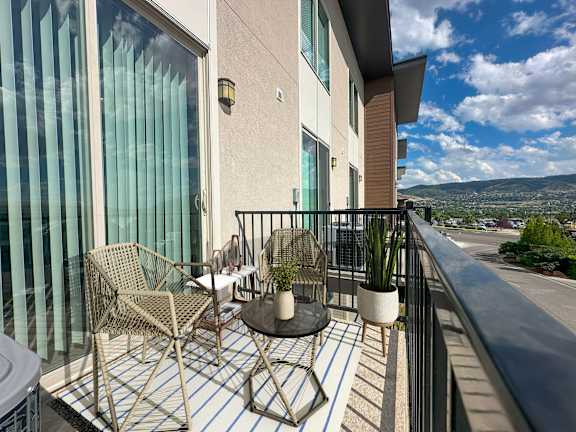 Private balcony with wicker furniture and city views at Liberty Point Apartments, Draper, Utah