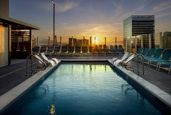 A swimming pool on a rooftop with sunset in the background.